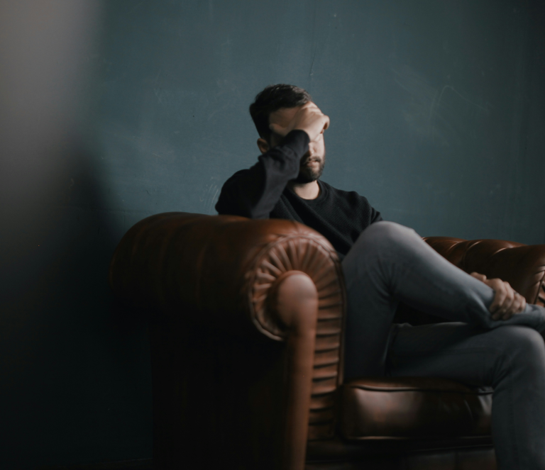 Man sitting in chair holding head